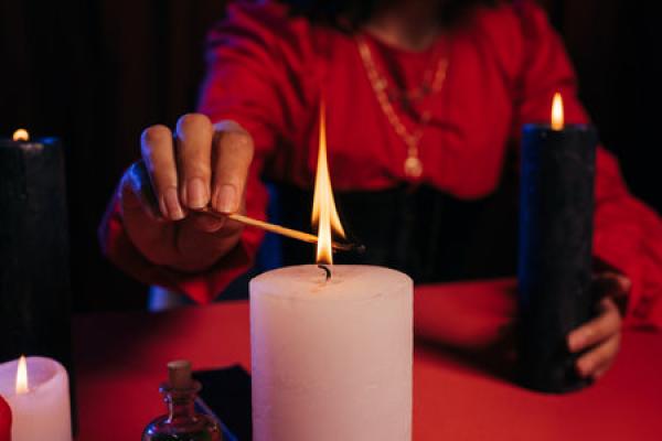 A woman is lighting a candle on a red table.