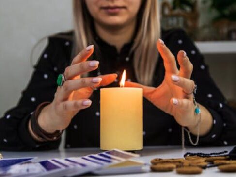 A woman is holding a candle with her hands.